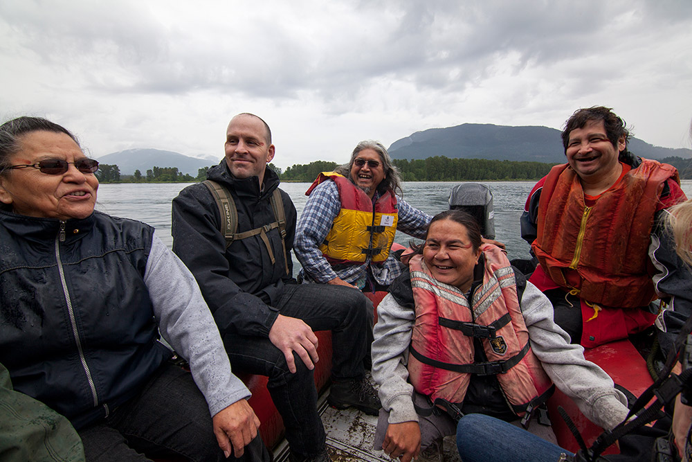 Five people are seated inside a small motorized boat, travelling across the river.