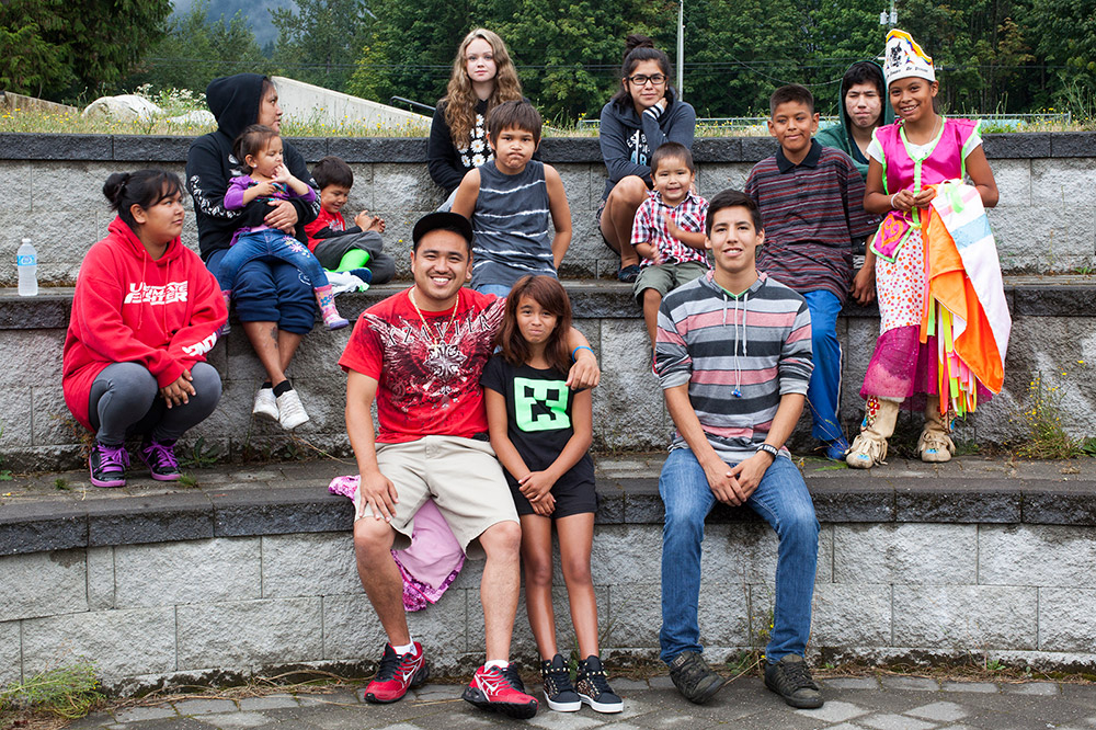 Youth, both male and female, are sitting outdoors on several rows of tiered stone seating.