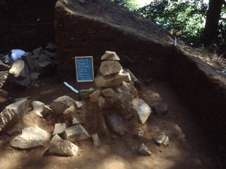 In a section of earth, a chalkboard and ruler are placed beside a tall pile of large rocks.