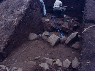 An archaeologist excavates part of an earthen mound.