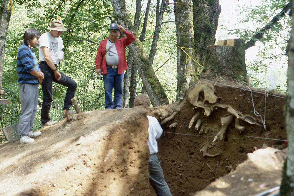 People gather on top of a large excavated archaeological mound.