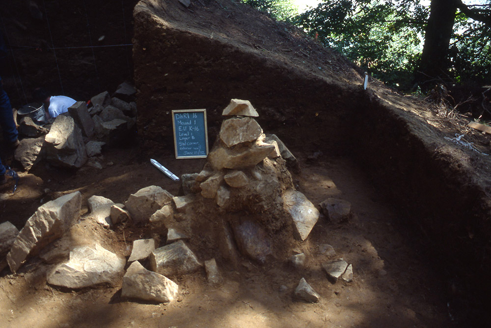 Dans une section de terre, un tableau et une règle sont placés à côté d’une pile de grosses roches.