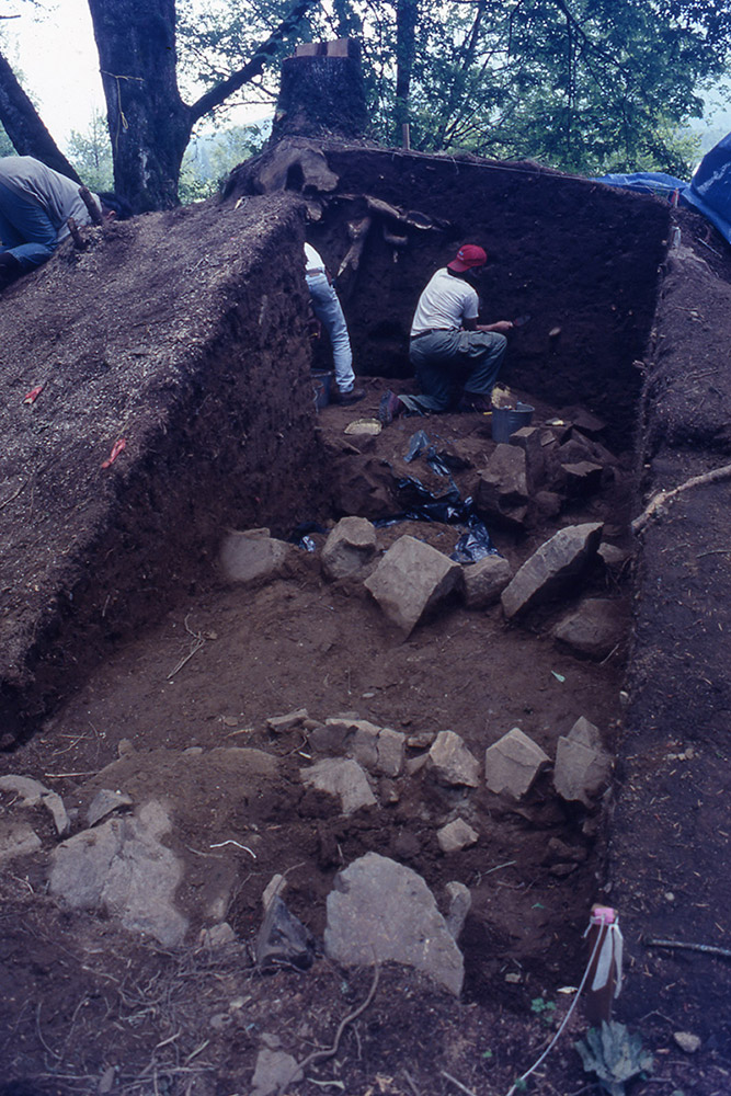 An archaeologist excavates part of an earthen mound.