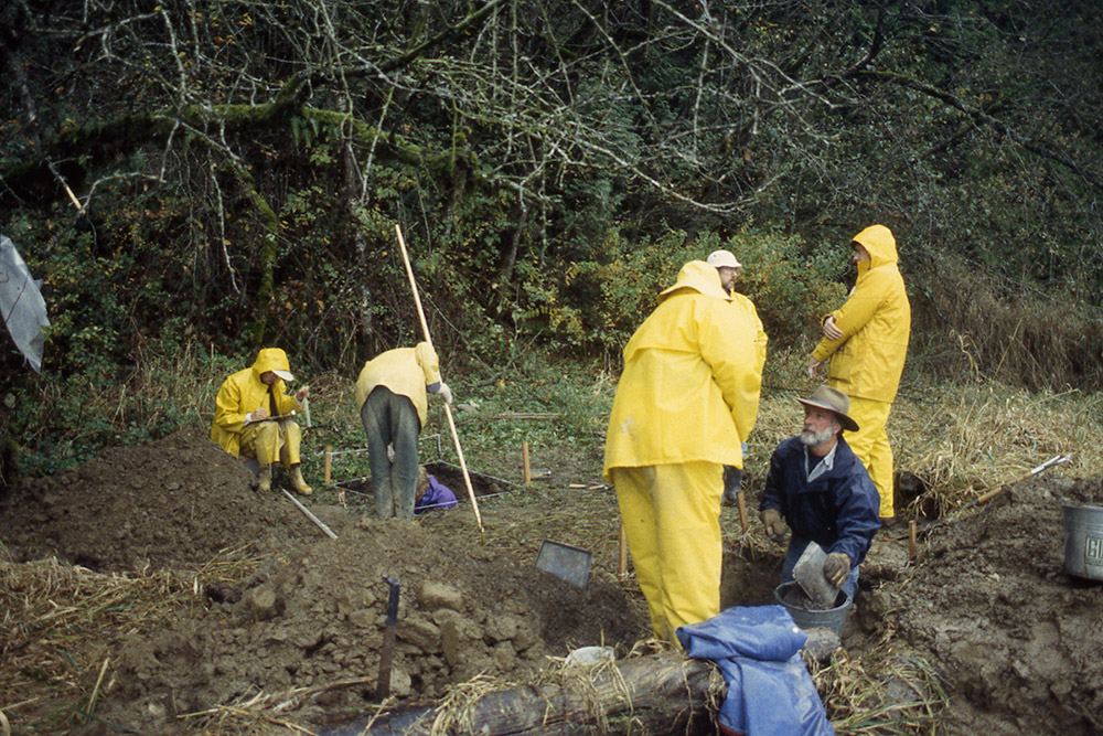 A group of people wearing raingear work in an archaeological area.