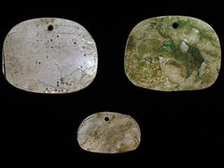 Three pieces of flat abalone shell shaped into ornaments.