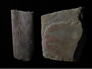 Deux morceaux de pierre grise façonnés en pièces carrées et plates.