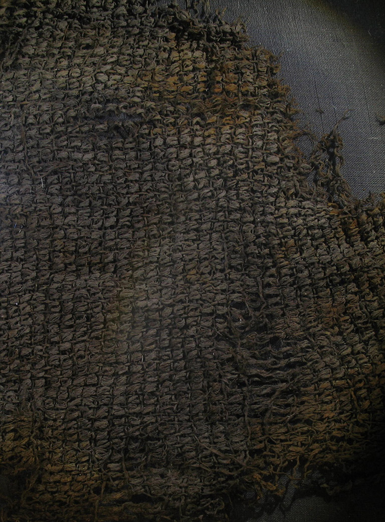 Un fragment d’un tissu à mailles serrées d’une couleur tirant sur le gris.