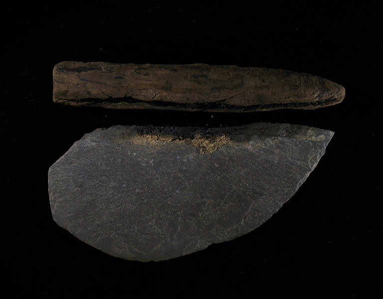 A dark grey stone shaped into a sharpened semi-circle, with the wooden handle detached.