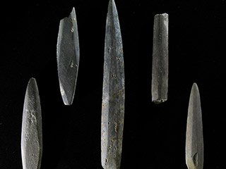 Five pieces of narrow stone are shaped into points. One has the point broken and another does not taper.