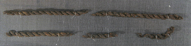 Three pieces of reddish brown fibre are woven into a braid to create a cord.