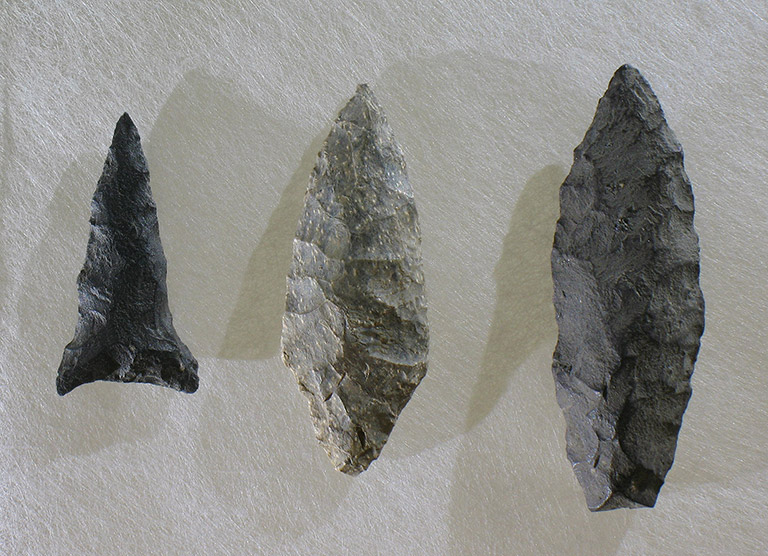 Three arrowheads of different sizes, and various shades of grey, on a white background.