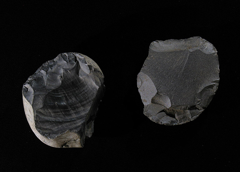 Two round, dark grey stones, with sharpened edges and smooth tops.