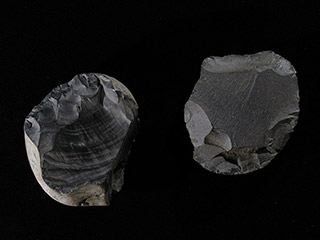 Two round, dark grey stones, with sharpened edges and smooth tops.