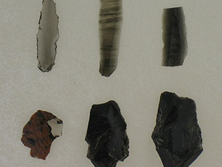 Three small, flat sharp rocks above three larger black amorphous rocks.