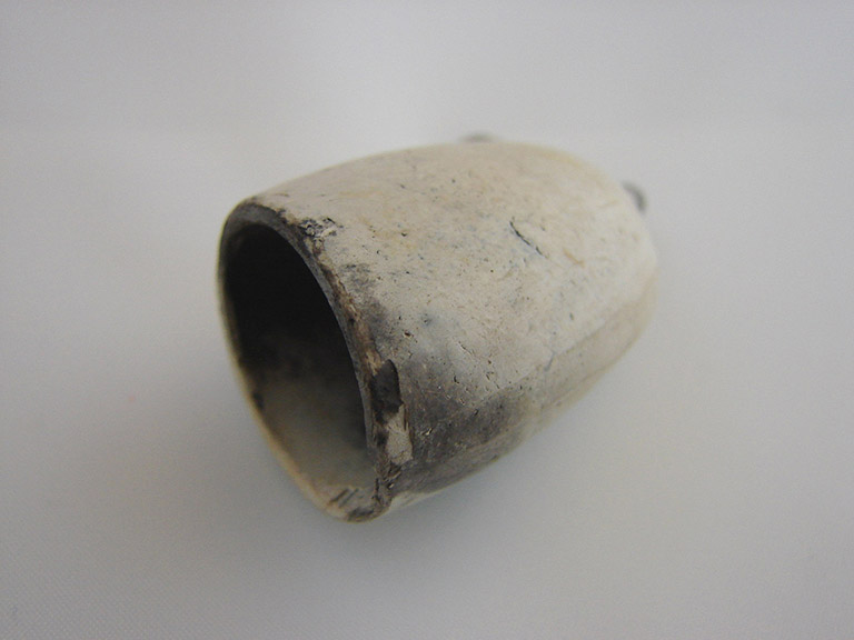 Smooth white hollow tube and smooth surfaced white hollowed cup that appear like pipe pieces.