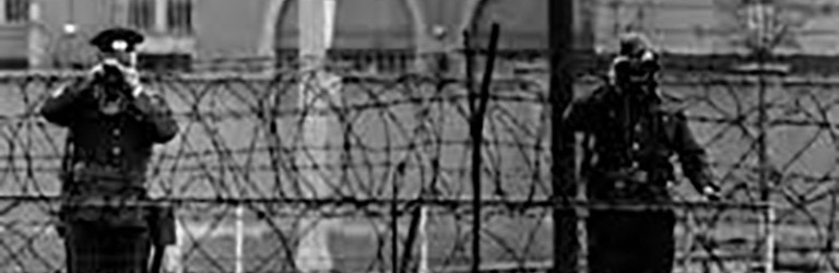 Soldiers scouting in a large wall topped with barbed wire