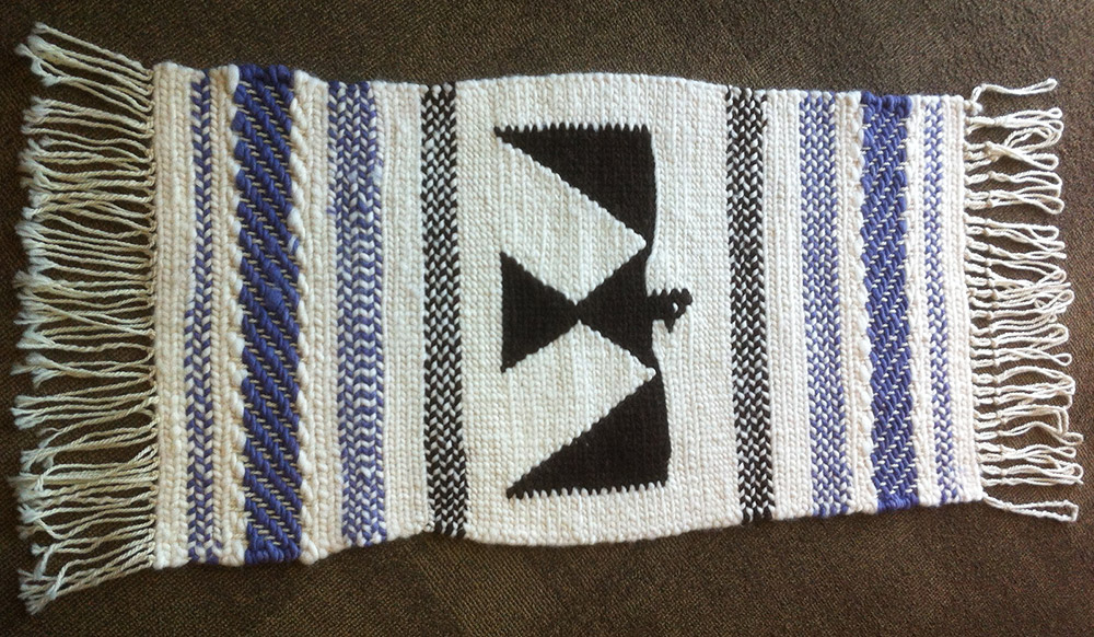 Tissage avec des rayures blanches et bleues aux extrémités et un motif d’oiseau-tonnerre au centre.