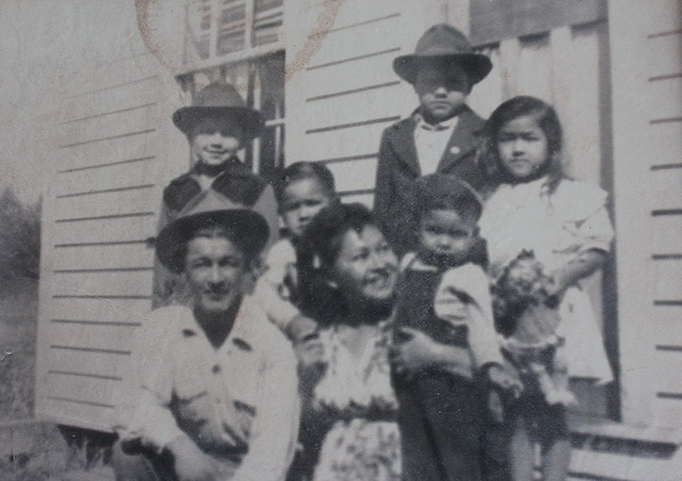 Une photo en noir et blanc d’une famille. L’homme et la femme sont accroupis à l’avant de la photo et il y a quatre enfants à l’arrière. La femme tient le plus jeune à côté d’elle.