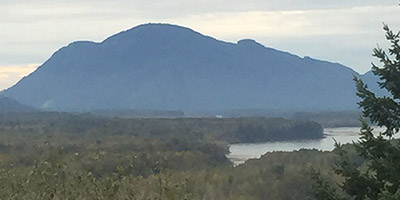 Une grosse colline abrupte au loin avec une vallée fluviale en-dessous.