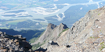 Un pic rocheux de montagne se détache sur un fond de ciel bleu.