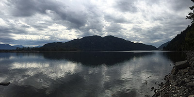 Une rivière reflète le ciel. Au loin, une montagne.