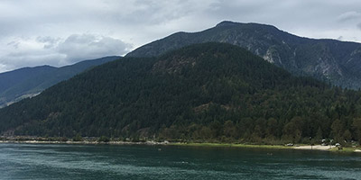 River reflecting the sky and forested mountain.