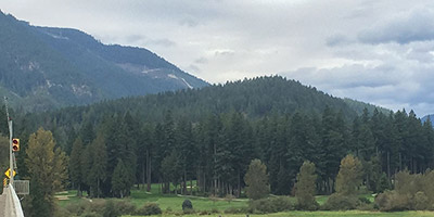 Un quai sur une rivière avec des battures herbeuses à l’arrière et des collines plus loin.