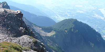 Power lines in the foreground and a tall forested mountain in the background.