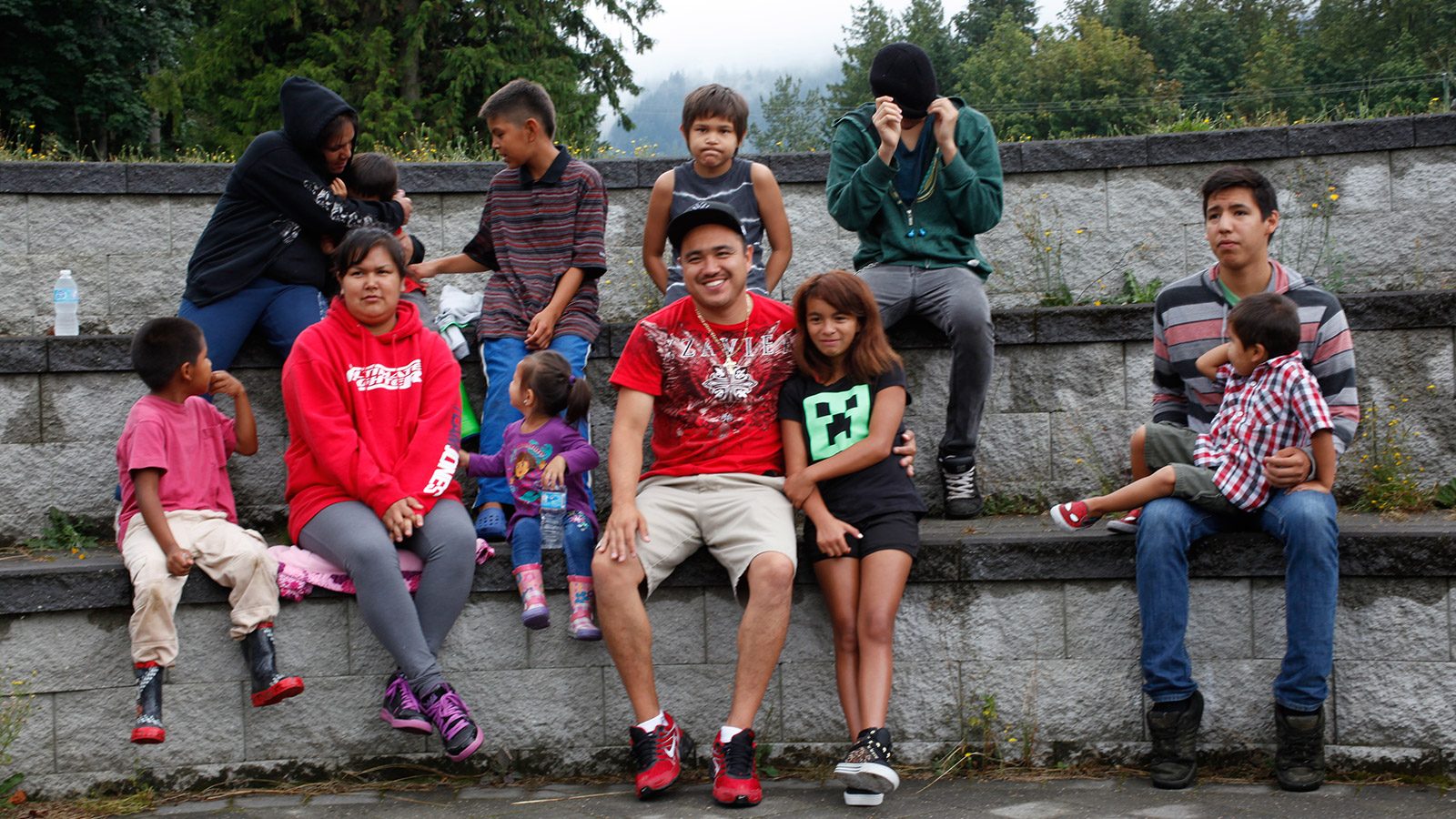 Des jeunes, garçons et filles, dehors, assis sur quelques rangées de pierre disposées en gradins.