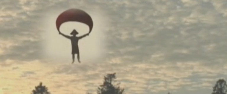 A figure with a cedar-root hat descends through the sky holding a parachute.